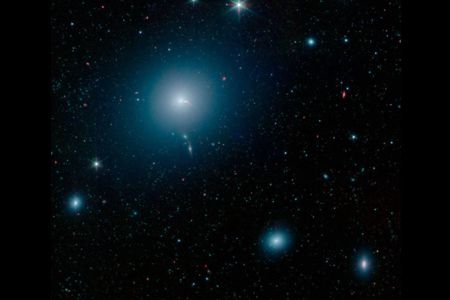 La galaxia M87 se ve como un nebuloso espacio azul en esta imagen del Telescopio Espacial Spitzer de la NASA. En el centro de la galaxia hay un agujero negro supermasivo que arroja dos chorros de material al espacio. Foto: NASA