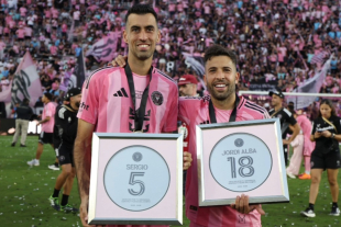 Jugadores del Inter Miami posan en la cancha con reconocimientos enmarcados, celebrando su trayectoria ante un estadio lleno de aficionados.