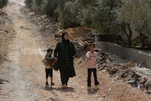 Una mujer y dos niños caminan cerca de la ciudad de Yenín, en Cisjordania